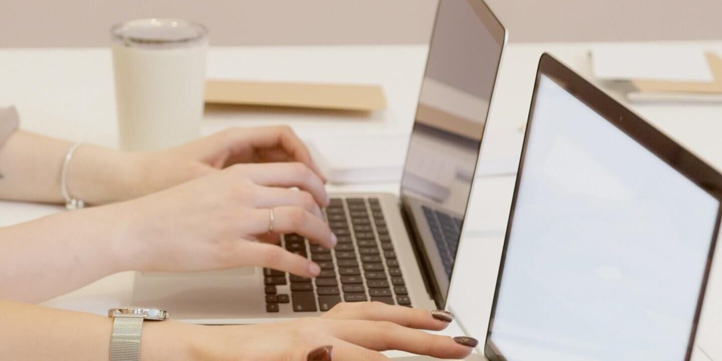 Two women working on laptops side by side.