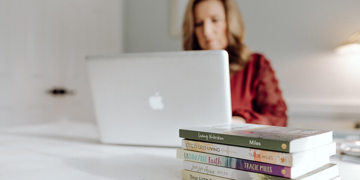 Tracie Miles with her books working on the laptop