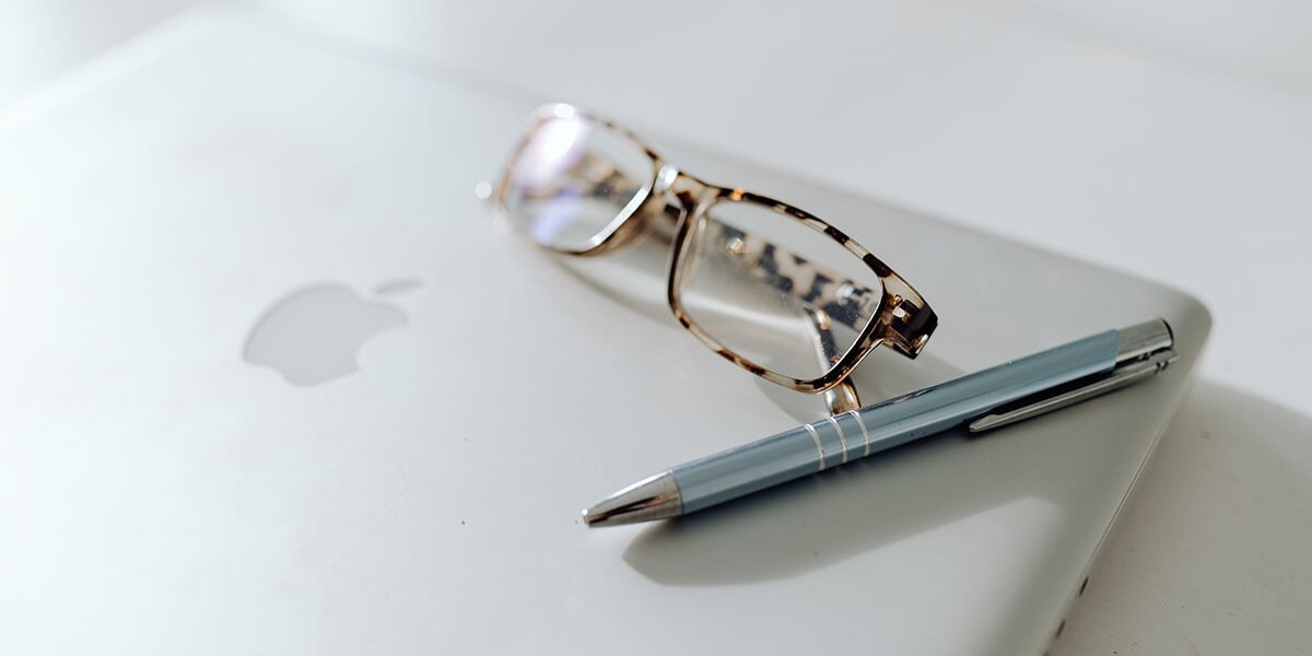 Laptop with glasses and a pen on top