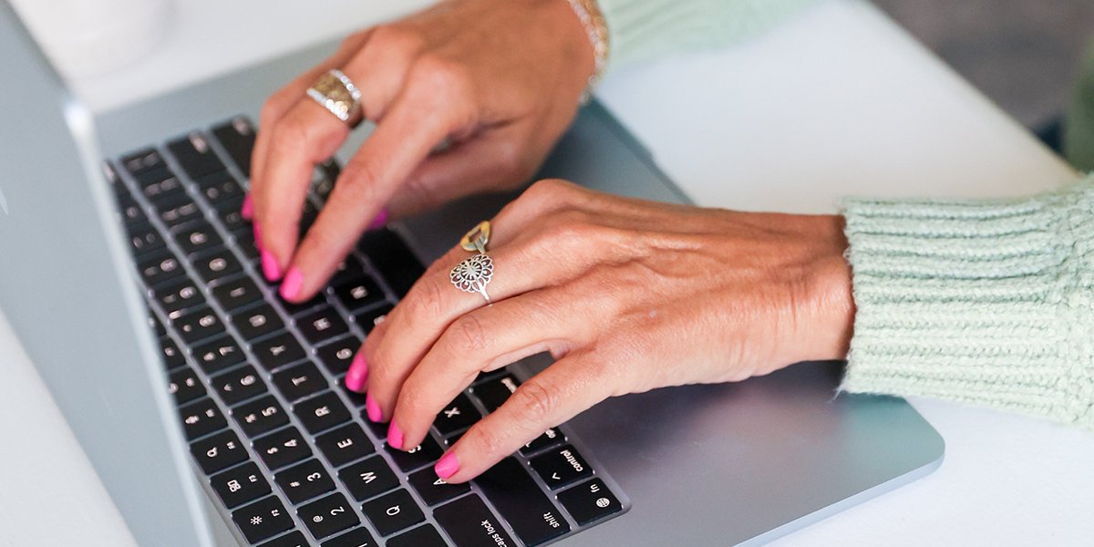 Woman Typing on laptop with reading glasses on the desk